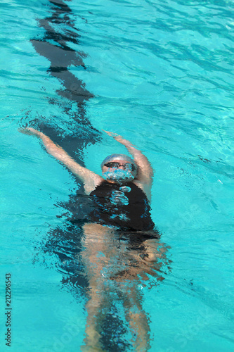 Young swimmer with silver swimming cap dive under water in the swimming pool for competition