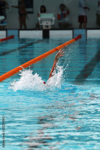 Swimmer swims backstroke or back crawl in a swimming pool for competition or race