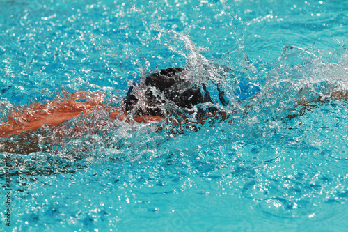 Young swimmer with black cap swim free style or forward crawl in a swimming pool for competition or race
