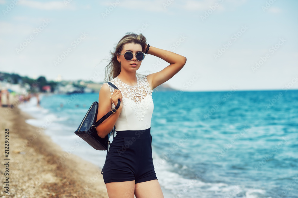 Attractive girl on the sea coast . Young stylish woman on a walk by the sea Attractive girl on the sea coast . Young stylish woman on a walk by the sea