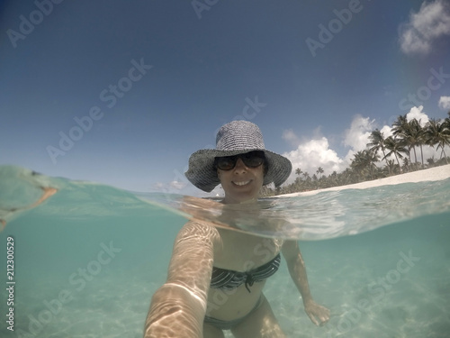 Selfie of a smiling middle aged woman in hat and shades in sea at Matautu, Lefaga, Upolu Island, Samoa, South Pacific photo