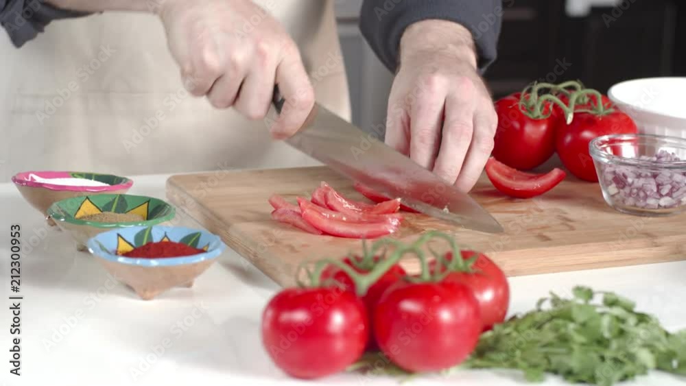Dolly shot of chef slicing ripe tomato with large kitchen knife Dolly shot of chef slicing ripe tomato with large kitchen knife