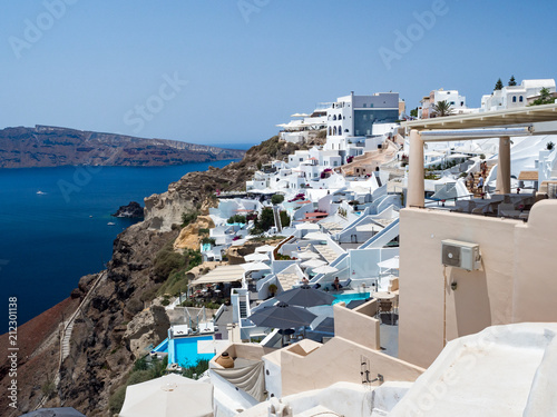 Oia village on Santorini island. Traditional and famous houses and churches with blue domes over the Caldera, Aegean sea. Greece, june 2018
