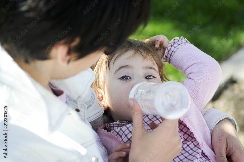 Mother feeding daughter from bottle