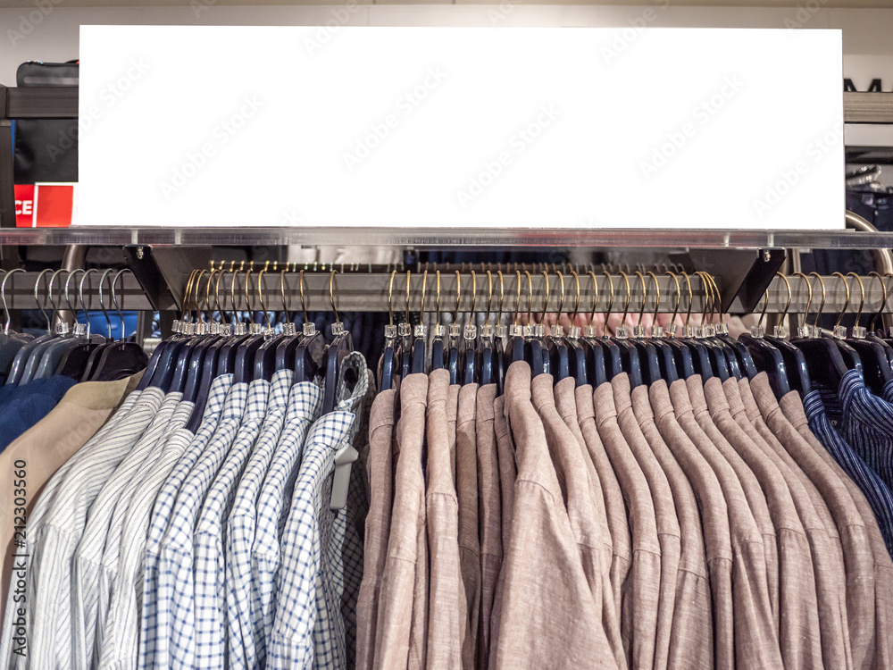Sales signage mock up template on men's clothing hanging rack in department store. Background texture of blank advertise display frame for apparel in shopping centre. Sales signage mock up template on men's clothing hanging rack in department store. Background texture of blank advertise display frame for apparel in shopping centre.