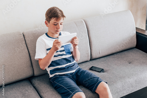 Teenager uses tablet at home sitting on couch