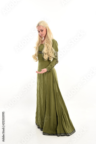 full length portrait of a blonde girl wearing green medieval gown, stand pose, isolated on white studio background.