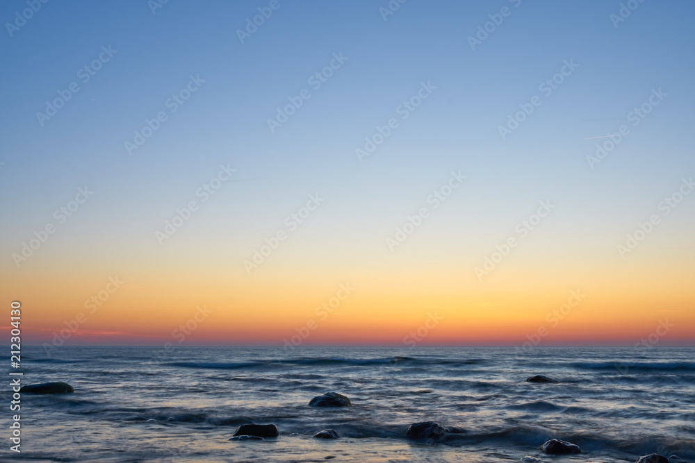 Ostsee mit Steinen im Wasser kurz nach dem Sonnenuntregang