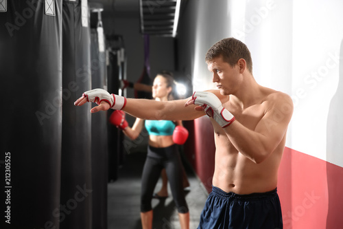 Male boxer training with punching bag in gym