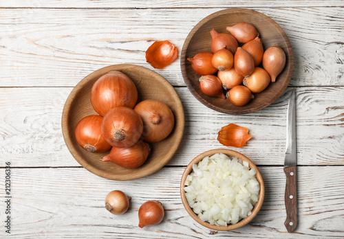 Flat lay composition with ripe onions on wooden background