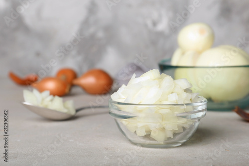 Glass bowl with cut onion on table