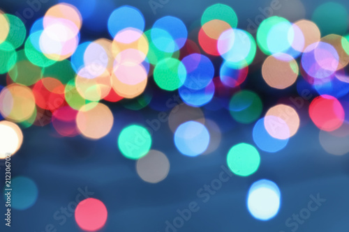 Blurred view of Christmas lights on color background