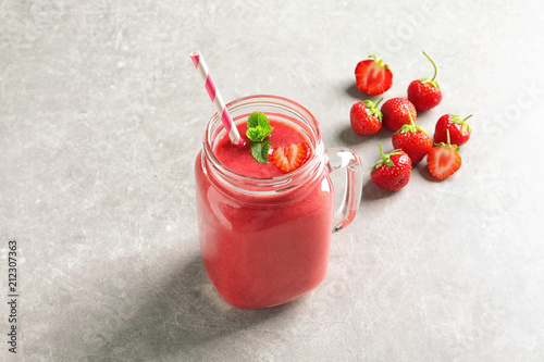 Mason jar with tasty strawberry smoothie on table
