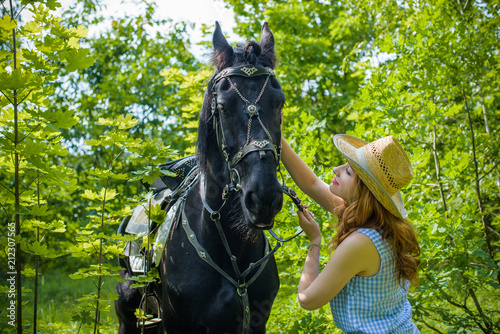 Nice american lady in a plaid shirt and hat. A beautiful rider gently hugs the horse. Artistic Photography at horse farm 