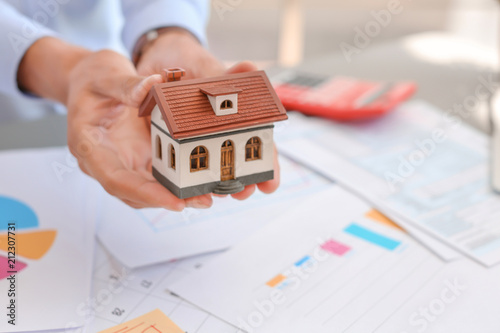 Man holding house model at table, closeup. Property tax
