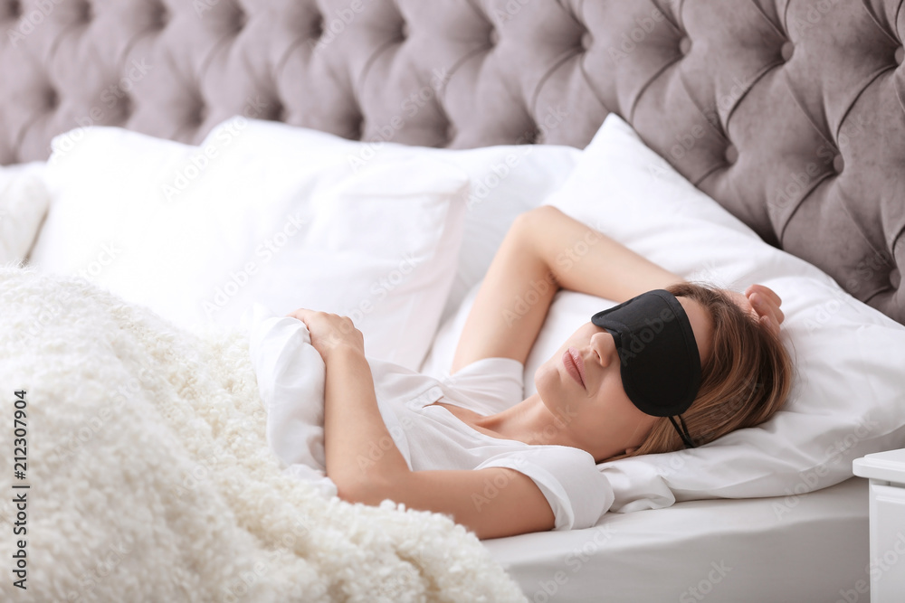 Fototapeta premium Young beautiful woman with mask sleeping in bed at home. Early morning