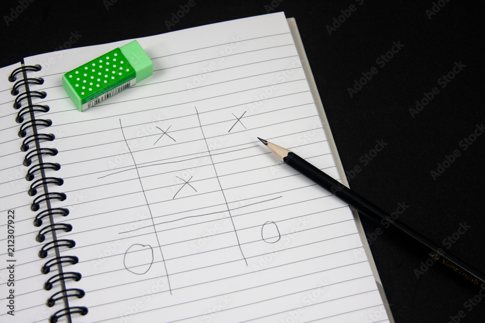 Naklejka premium Playing Tic Tac Toe on the note book.