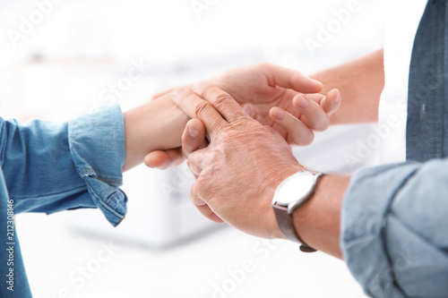 Senior man checking young woman's pulse on blurred background
