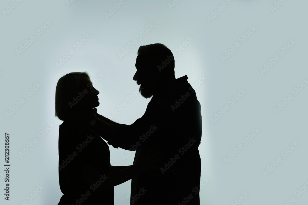 Silhouette of man strangling his wife on color background. Relationship problems