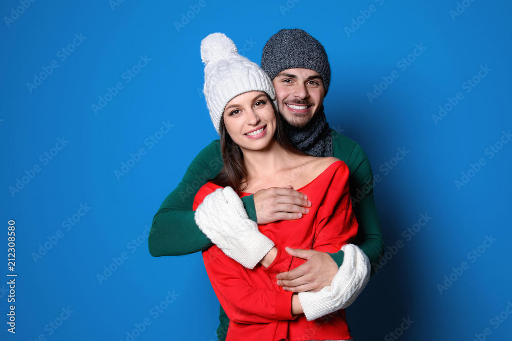 Young couple in warm clothes on color background. Christmas celebration Young couple in warm clothes on color background. Christmas celebration