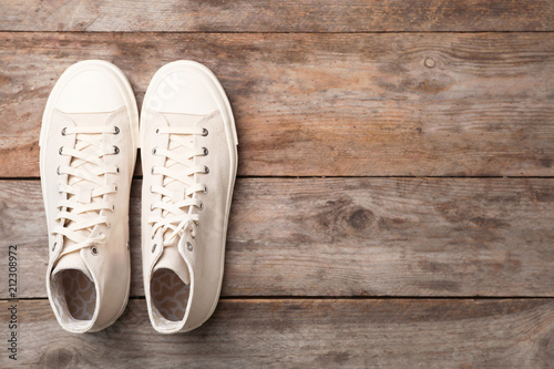 Pair of white sneakers on wooden background, top view