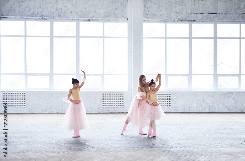 Naklejka premium Teacher trains ballet moves with little girls in pink clothes in the room