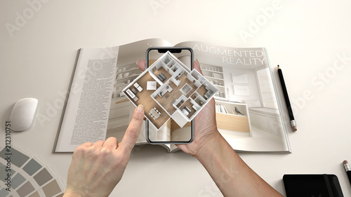 Augmented reality concept. Hand holding smartphone with AR application used to simulate 3d pop-up interactive house maps to life photo