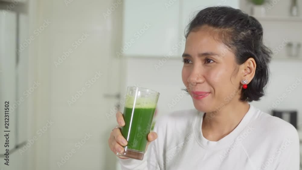 Happy woman drinking a glass of vegetables juice in the kitchen at home. Shot in 4k resolution Happy woman drinking a glass of vegetables juice in the kitchen at home. Shot in 4k resolution