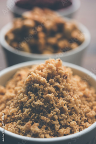 Crushed peanuts or mungfali powder with whole and roasted groundnut. Served in a bowl over moody background. Selective focus photo