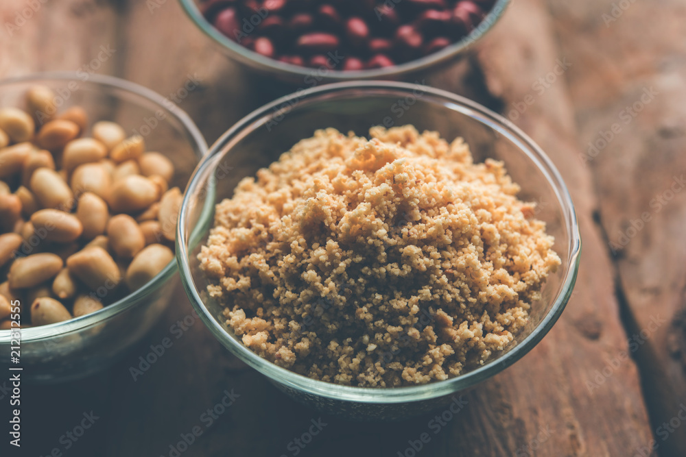 Crushed peanuts or mungfali powder with whole and roasted groundnut. Served in a bowl over moody background. Selective focus Crushed peanuts or mungfali powder with whole and roasted groundnut. Served in a bowl over moody background. Selective focus