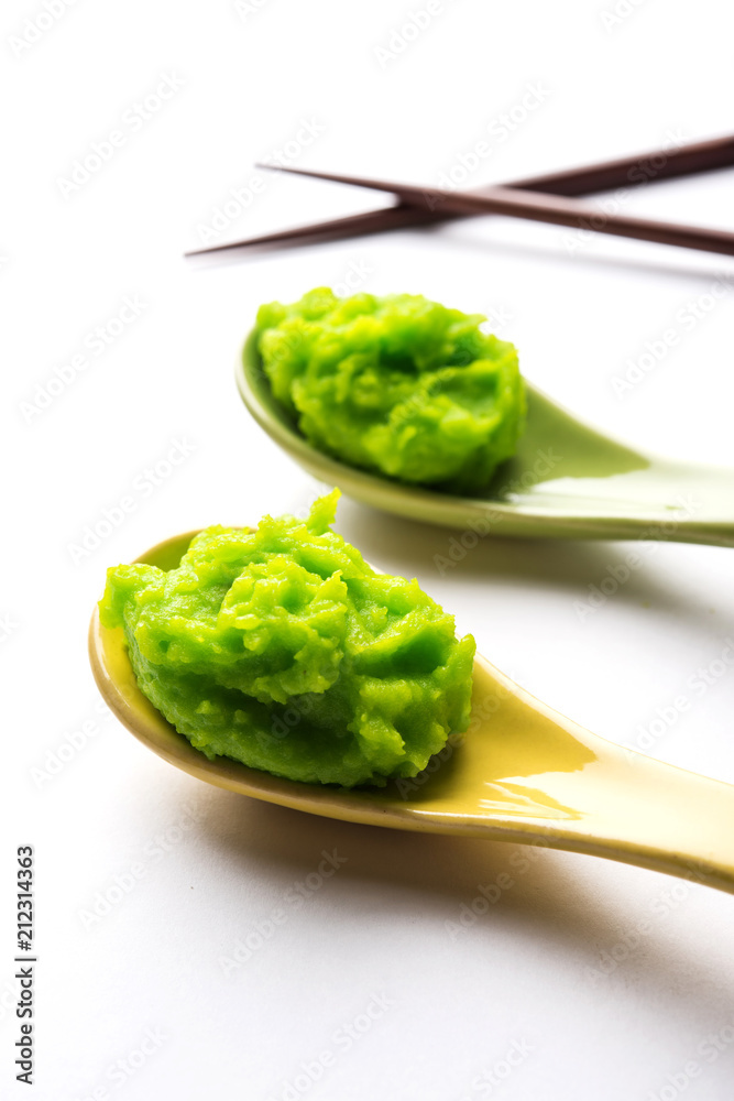 Green wasabi sauce or paste in bowl, with chopsticks or spoon over plain colourful background. selective focus Green wasabi sauce or paste in bowl, with chopsticks or spoon over plain colourful background. selective focus