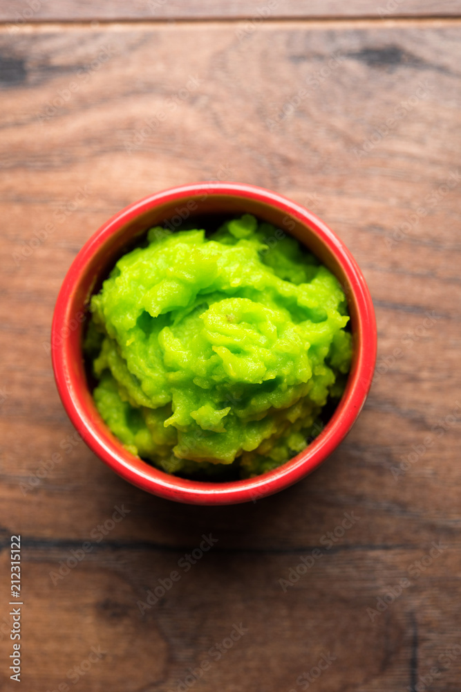Green wasabi sauce or paste in bowl, with chopsticks or spoon over plain colourful background. selective focus