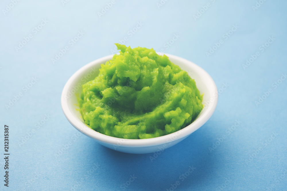 Green wasabi sauce or paste in bowl, with chopsticks or spoon over plain colourful background. selective focus Green wasabi sauce or paste in bowl, with chopsticks or spoon over plain colourful background. selective focus