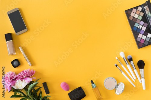 Flat lay and top view of make up products on yellow summer background with copyspace. Beauty concept for blogger, fashion women business office table desk photo