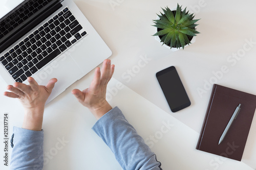 Top view of casual businessman working on a laptop at office desk with laptop, mibile phone and notebook, flat lay photo