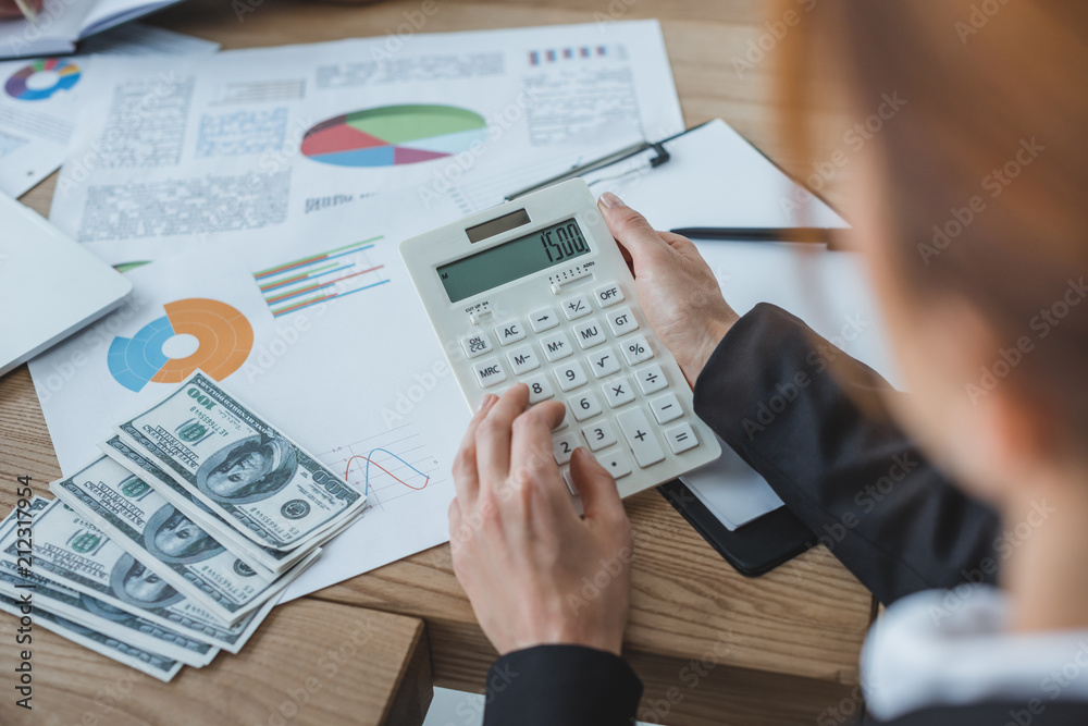 cropped image of financier using calculator at work in office cropped image of financier using calculator at work in office