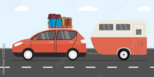 Modern red car with luggage on roof and caravan