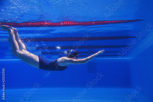 beautiful young girl with a good figure swims under water, effectively dives