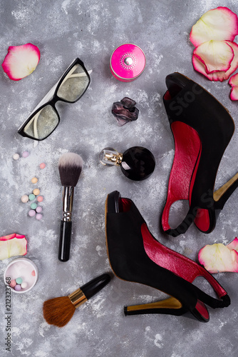 Still life of fashion woman. Women's fashion with petals of roses, cosmetics, glasses and shoes on stone background, photo