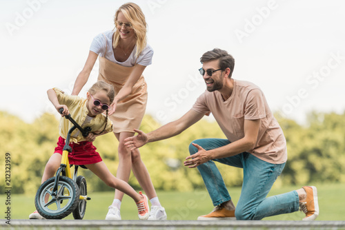happy parents looking at cute little daughter riding bicycle in park © LIGHTFIELD STUDIOS