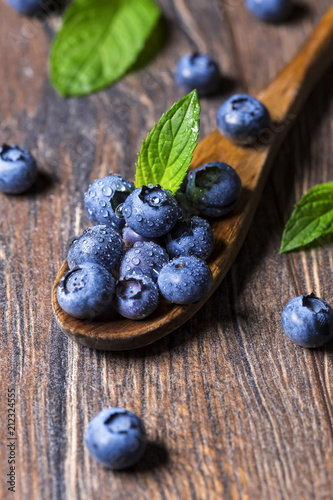 Fresh blueberries and mint leaf on wooden spoon. Macro shot of blueberry fruit.