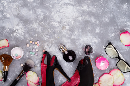 Still life of fashion woman. Women's fashion with petals of roses, cosmetics, glasses and shoes on stone background, copy space photo