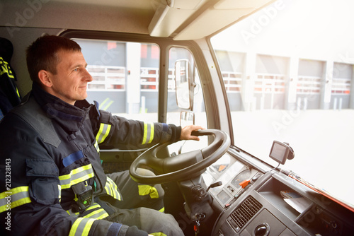 smiling fireman at the wheel of a fire truck drives to work