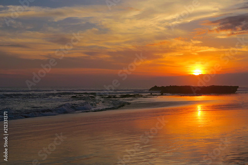 Orange tropical sunset with reflection at Canggu beach  Bali  Indonesia
