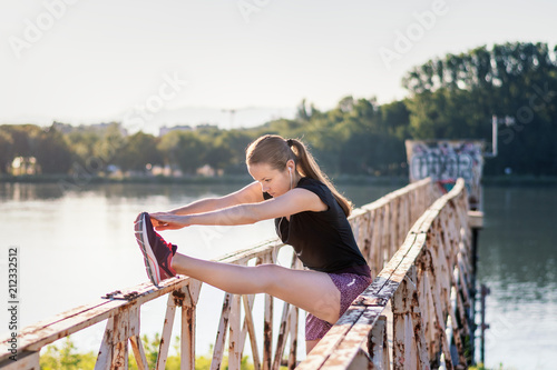 Sport and fitness. Young woman training outdoor at sunrise with urban background. © PhotoGranary
