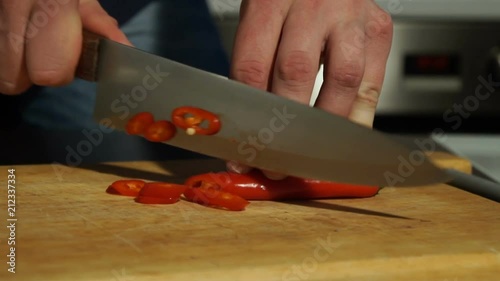 Slicing Red chili pepper. A man cuts pepper on a wooden Board photo