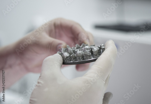 Man holds in hands object printed on metal 3d printer in laboratory. Dental crowns created in laser sintering machine close-up. DMLS  SLM  SLS technology. 4.0 industrial revolution.