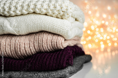 Warm sweaters. Pile of knitted clothes on warm background, sweaters, knitwear, space for text, Autumn winter concept. Copy Space