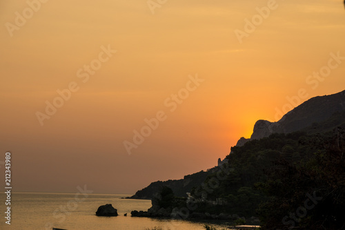 beautiful sunset over the ocean and cliffs in corfu  greece soft orange color