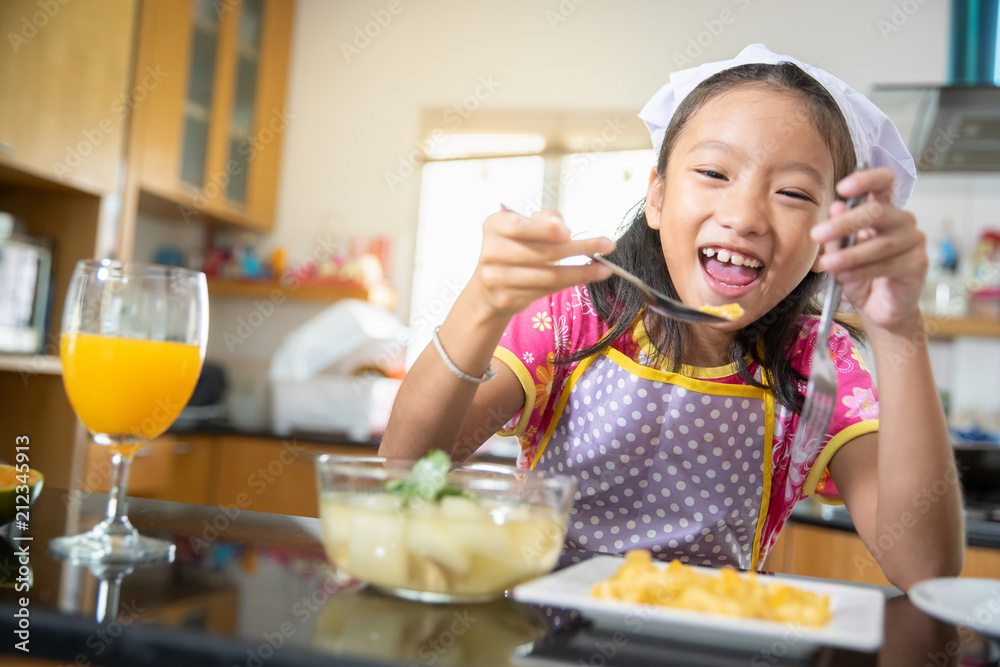 Little girl enjoy eating food with orange juice in kitchen Little girl enjoy eating food with orange juice in kitchen
